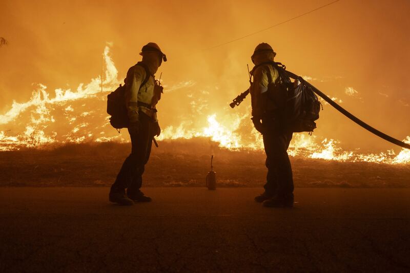 Firefighters watch as the Hughes Fire quickly approaches after it tore through northern Los Angeles County