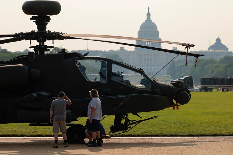 WASHINGTON, DC - JUNE 11: People pause to look at a U.S. Army AH-64 Apache attack helicopter parked on display on the National Mall on June 11, 2025 in Washington, DC. The nation's capital is preparing for weekend events celebrating the 250th anniversary of the founding of the U.S. Army.
