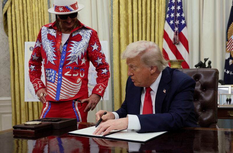 U.S. President Donald Trump signs an executive order related to the U.S. live entertainment ticketing industry, next to Kid Rock, in the Oval Office at the White House in Washington, D.C., March 31, 2025.   REUTERS/Leah Millis