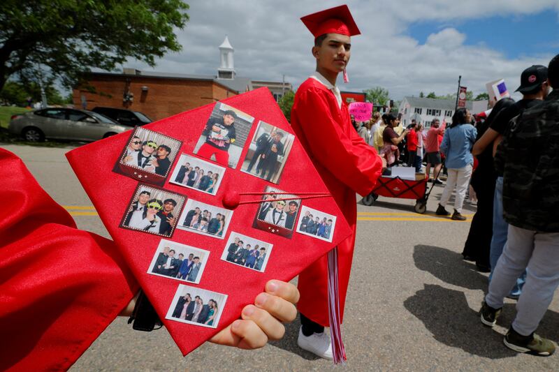 A friend of high school student Marcelo Gomes shows photographs of Gomes on his graduation cap.
