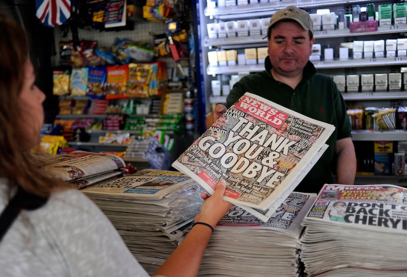 A woman buys a copy of the last edition of the British tabloid newspaper News of the World.