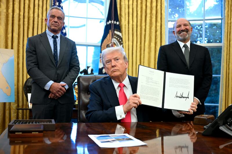 US President Donald Trump holds an Executive Order, alongside US Secretary of Health and Human Services Robert F. Kennedy Jr. (L) and US Secretary of Commerce nominee Howard Lutnick (R), at the Oval Office of the White House in Washington, DC on February 25, 2025.
