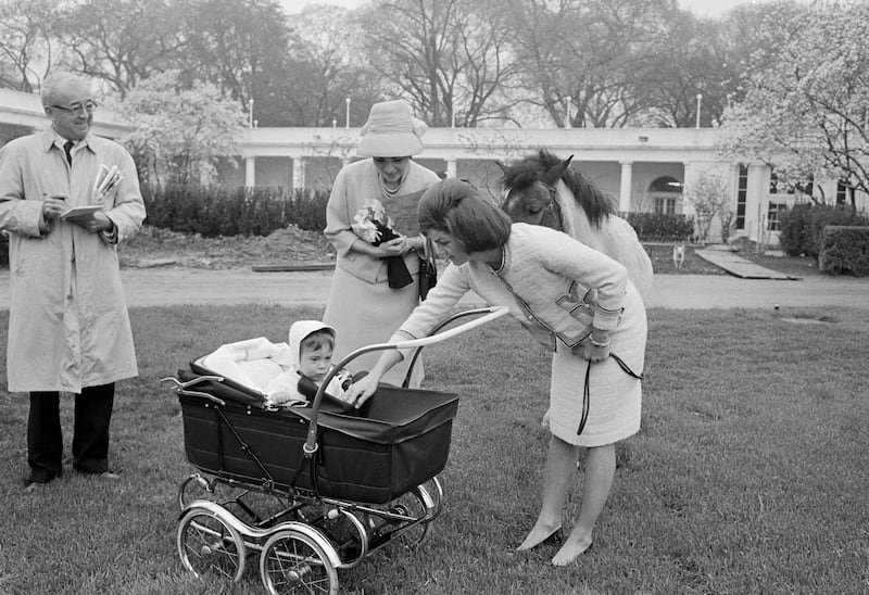 Jacqueline Kennedy introduces her son, John as she takes the wife of the Shah of Iran on a tour of the white House grounds.