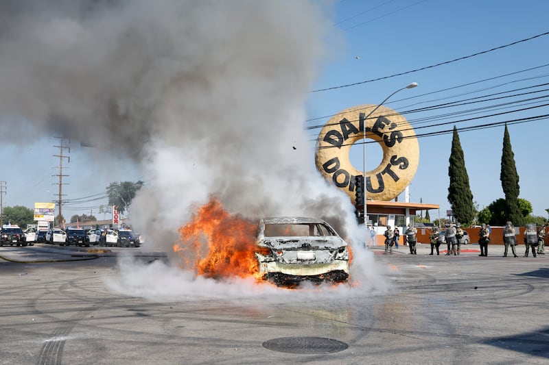 A car burns in the middle of the intersection of Atlantic Ave. and E Alondra Blvd. during ICE protests on Saturday, June 7, 2025 in Los Angeles, CA.