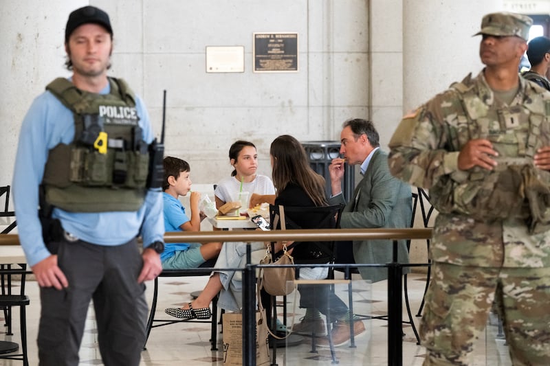 A family eats Shake Shack as a member of the National Guard and U.S. Marshalls stand  watch while Vice President JD Vance and Secretary of Defense Pete Hegseth met with service members at Union Station in Washington, DC, August 20, 2025.