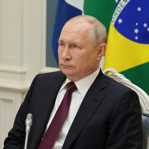 Russian President Vladimir Putin frowns in front of several flags at press conference