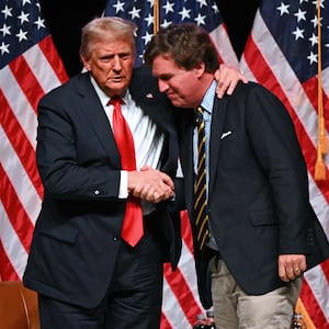 Former US President and Republican presidential candidate Donald Trump (L) shakes hands with US commentator Tucker Carlson at the end of a live interview in the finale of the Tucker Carlson Live Tour at Desert Diamond Arena in Glendale, Arizona, on October 31, 2024. (Photo by Patrick T. Fallon / AFP) (Photo by PATRICK T. FALLON/AFP via Getty Images)