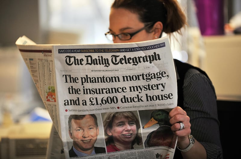 A woman reads a copy of the Daily Telegraph newspaper in London.