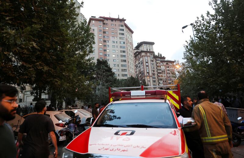 People gather in the street near an emergency vehicle in the aftermath of Israeli strikes, in Tehran, Iran, June 13, 2025.