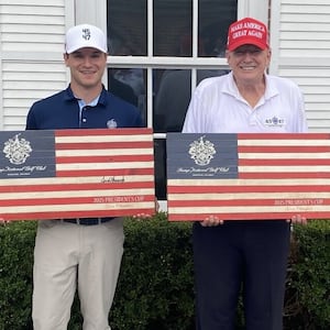 Donald Trump (right) commemorative American flags while next to his golf partner, Thomas Urciuoli.