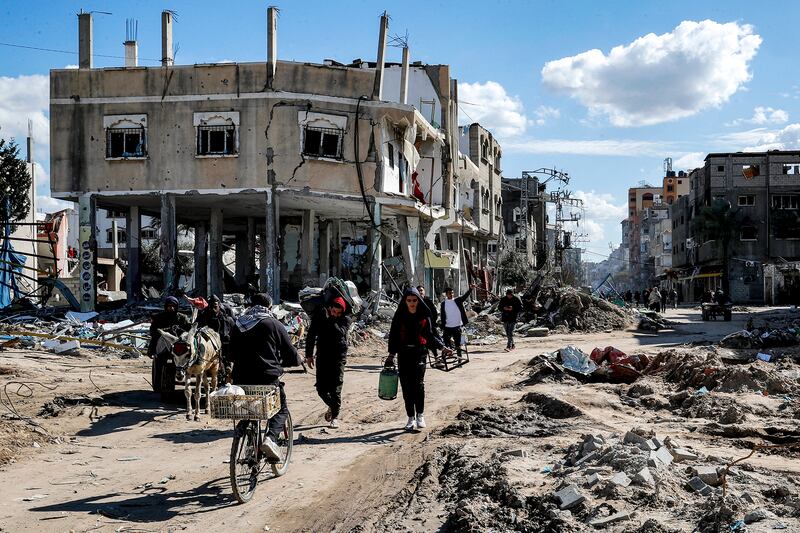 People walk past destroyed buildings destroyed by Israeli bombardment in the Maghazi camp in Gaza.