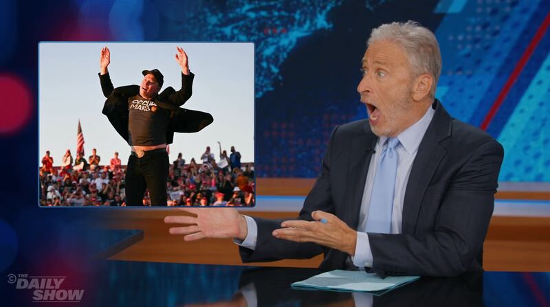 Daily Show, Jon Stewart showing an image of happy Elon Musk