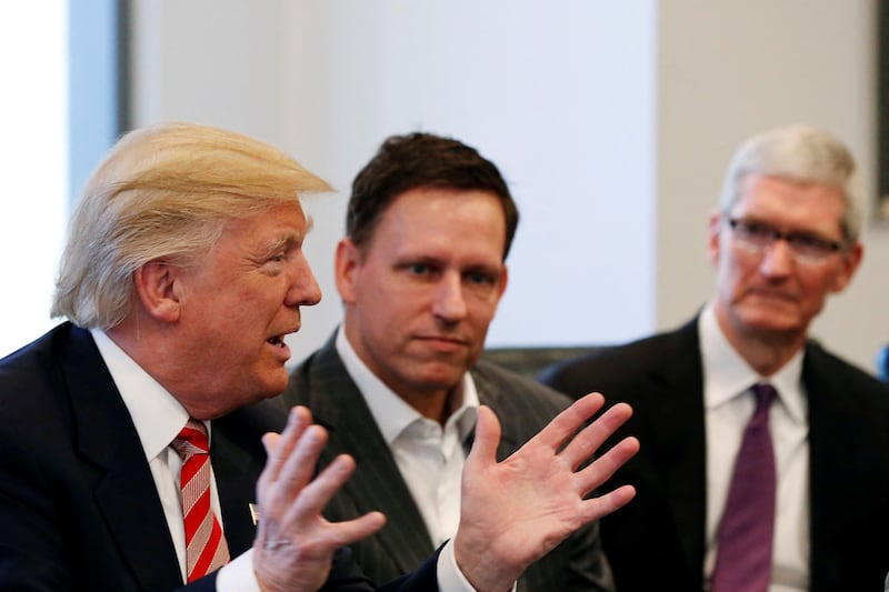 President Donald Trump speaks in 2016 with Peter Thiel, left, and Apple Inc. CEO Tim Cook, right, behind him.