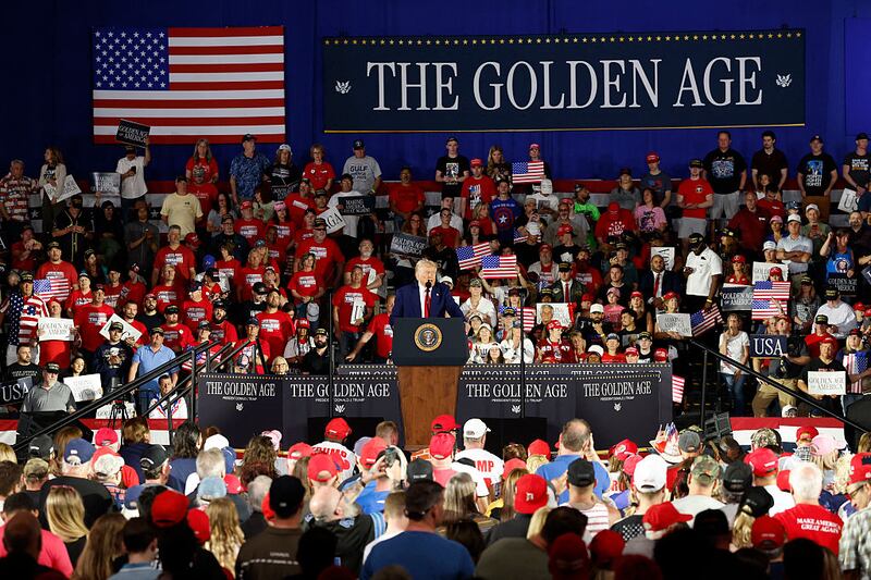 President Donald Trump delivers a speech in Michigan to mark his 100th day in office, underneath a banner that says “The Golden Age.”