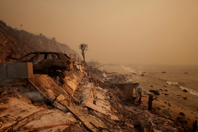 A burned car sits next to the remains of a home destroyed during the Palisades Fire in Malibu.