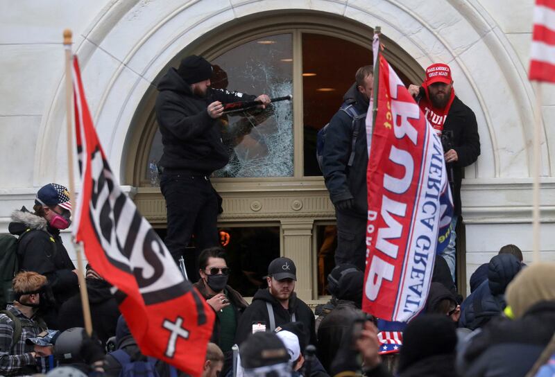 A man breaks a window as a mob of supporters of U.S. President Donald Trump storm the U.S. Capitol Building in Washington, U.S., January 6, 2021