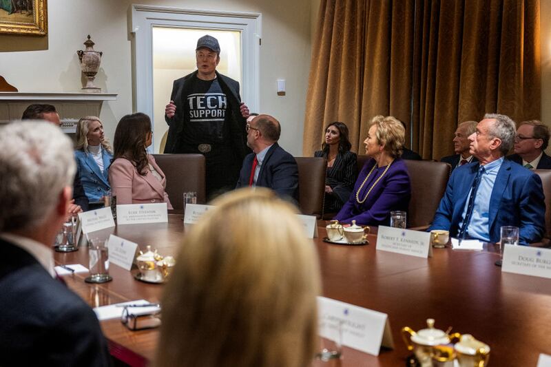 Elon Musk appears at a cabinet meeting wearing a shirt that says "Tech Support."