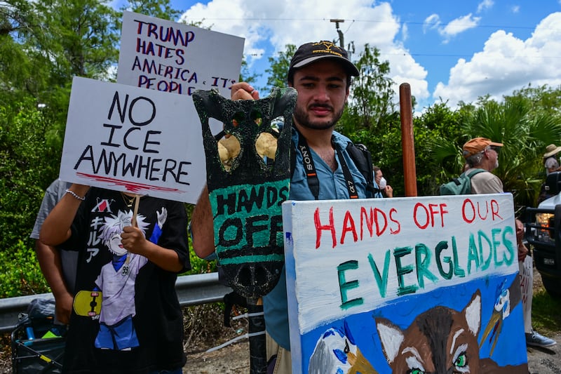 Demonstrators hold signs as they protest Trump's visit to a migrant detention center, dubbed "Alligator Alcatraz," located at the site of the Dade-Collier Training and Transition Airport in Ochopee, Florida on July 1, 2025.