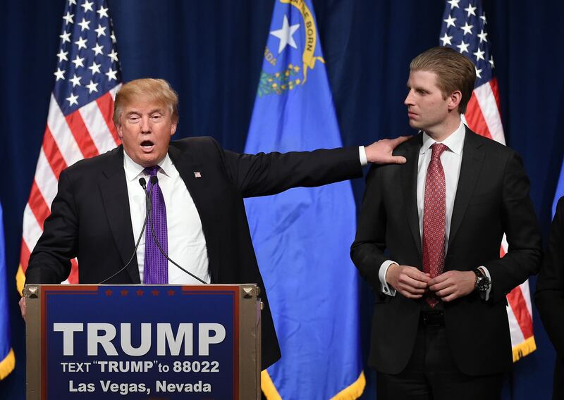 Donald Trump (L) speaks as his son Eric Trump looks on.