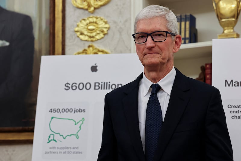 Apple CEO Tim Cook stands, as he along with U.S. President Donald Trump (not pictured) present Apple's announcement of a $100 billion investment in U.S. manufacturing, in the Oval Office at the White House in Washington, D.C., U.S., August 6, 2025.