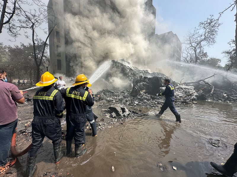 Rescue team members work as smoke rises at the site where an Air India plane crashed in Ahmedabad, India, June