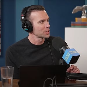 Pod Save America host Jon Favreau speaks into a microphone.