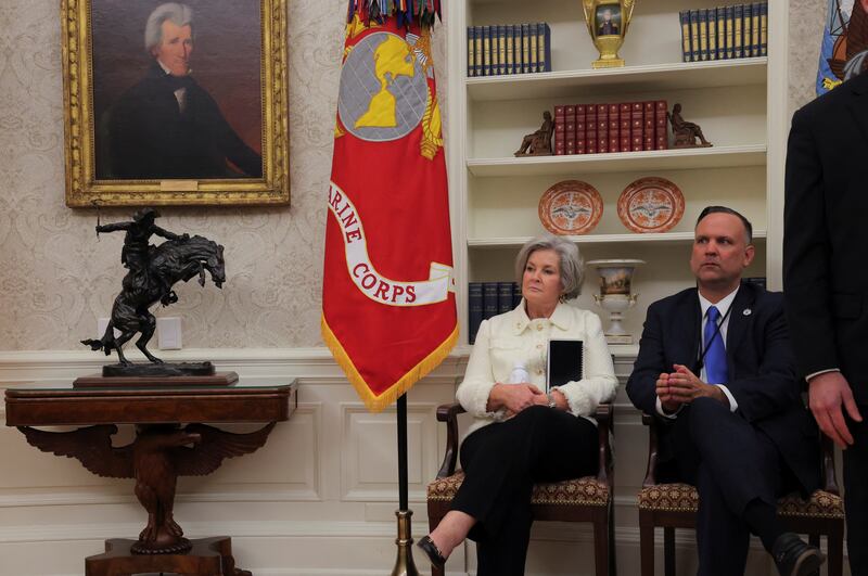 President Donald Trump's Chief of Staff Susie Wiles sits with Dan Scavino in the Oval Office on Inauguration Day. Some of Trump’s early changes to the office, like the inclusion of Andrew Jackson’s portrait and the placement of U.S. military flags, can be seen. Six months in, that same area is now filled with gold trinkets and accents.