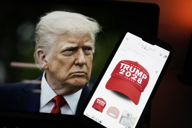 This photo illustration, taken on April 24, 2025, in Washington, DC, shows an image of US President Donald Trump alongside a smartphone displaying a red 'Trump 2028' cap on the Trump Store website. Donald Trump's online store is selling clothing emblazoned "Trump 2028," the year of the next US presidential election, in which the Republican is constitutionally banned from running. The 78-year-old, who has seen his approval rating sink in recent opinion polls, has not ruled out serving a third term -- though most spectators consider that highly unlikely. (Photo by Oliver Contreras / AFP) (Photo by OLIVER CONTRERAS/AFP via Getty Images)