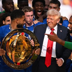 Members of Chelsea FC try to get President Trump off the stage so they can celebrate.