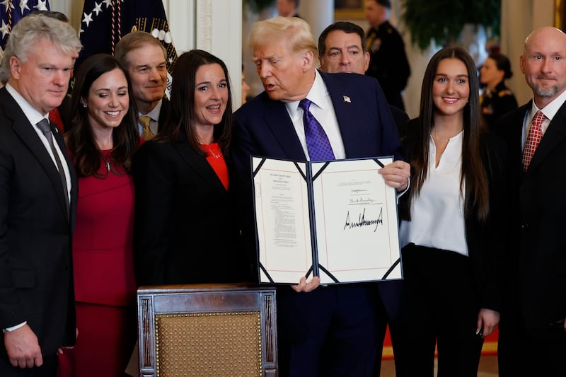 WASHINGTON, DC - JANUARY 29: Surrounded by members of Congress and the family of Laken Riley, U.S. President Donald Trump poses with the signed Laken Riley Act, the first piece of legislation passed during his second term in office, in the East Room of the White House on January 29, 2025 in Washington, DC. Jason Riley and Allyson Philips, the parents of 22-year-old Laken Riley, a University of Georgia nursing student who was murdered in 2024 by an undocumented immigrant, attended the signing ceremony. Among other measures, the law directs law enforcement authorities to detain and deport immigrants who are accused but not yet convicted of specific crimes, if they are in the country illegally.  (Photo by Chip Somodevilla/Getty Images)