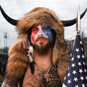 Jacob Chansley, also known as Jake Angeli, with his face painted in the colors of the U.S. flag, poses for a picture as supporters of U.S. President Donald Trump gather.