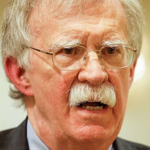 Split of images showing John Bolton on the left and on the right, FBI agents walk outside the house of John Bolton, Donald Trump's former national security advisor after the FBI conducted a court-authorized search at his place on August 22, 2025 in Bethesda, Maryland.