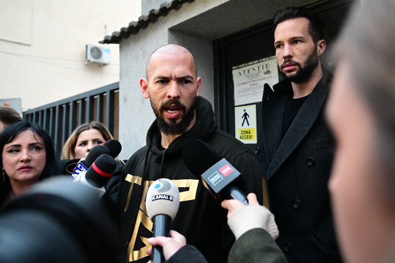 TOPSHOT - British-US former professional kickboxer and controversial influencer Andrew Tate (C) and his brother Tristan Tate (back R) speak to journalists after having been released from detention in Bucharest, Romania on March 12, 2024, after they appeared in a court after Romanian police detained them over UK sex offence charges. A Bucharest court on March 12 granted a request to extradite controversial influencer Andrew Tate to the UK over sex offence charges, but only after the conclusion of legal proceedings in Romania in a separate case. The Bucharest appeals court ruling "orders the execution of the warrant of arrest issued on 19 January 2024" by the Westminster Magistrates' Court, but postpones extradition "until the final resolution of the case" in Romania, which could take years. (Photo by Daniel MIHAILESCU / AFP) (Photo by DANIEL MIHAILESCU/AFP via Getty Images)