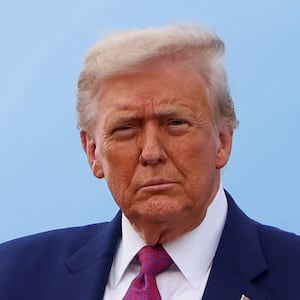 U.S. President Donald Trump holds a USA hat as he disembarks Air Force One upon arrival at Pope Army Airfield, in North Carolina, U.S., June 10, 2025.