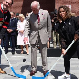 Britain’s King Charles III  (C) drops a puck with former Ottawa Senators hockey player Chris Philips (L) and soccer player Desriee Scott during a street hockey game at a community event in Lansdowne Park in Ottawa, Canada, May 26, 2025.