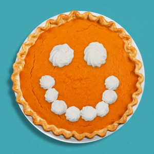 thanksgiving pumpkin pie with a smiley face of whipped cream winking