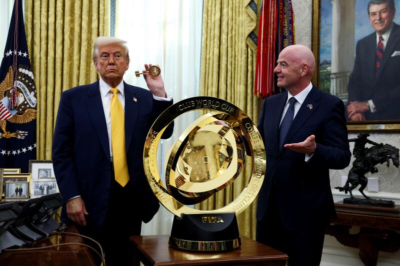 President Donald Trump and FIFA President Gianni Infantino stand next to the FIFA Club World Cup trophy in the Oval Office.