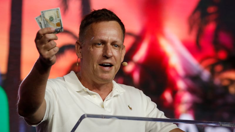Peter Thiel holds hundred dollar bills as he speaks during the Bitcoin 2022 Conference