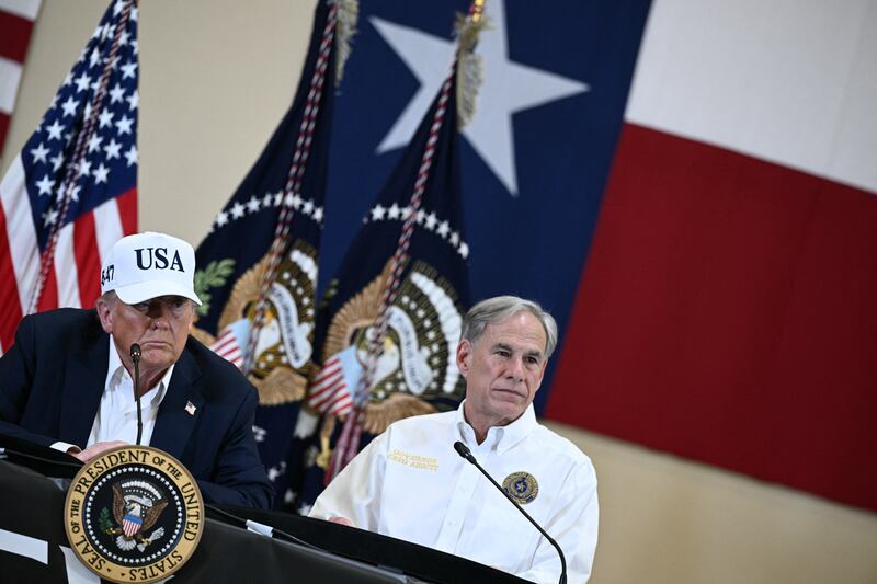 President Donald Trump and Texas Governor Greg Abbott speak during a meeting with local officials and first responders in Kerrville, Texas, on July 11, 2025, following devastating flooding that occurred in the area over the July 4 weekend.