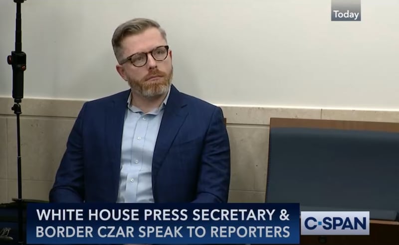 Rogan O'Hanley sitting on a chair against a wall wearing a blue suit. "White House Press Secretary & border czar speak to reporters." C-Span