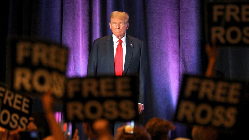 People hold signs in support of jailed darknet market Silk Road founder Ross Ulbricht, as former U.S. President and Republican presidential candidate Donald Trump attends the Libertarian Party's national convention in Washington, U.S., May 25, 2024.