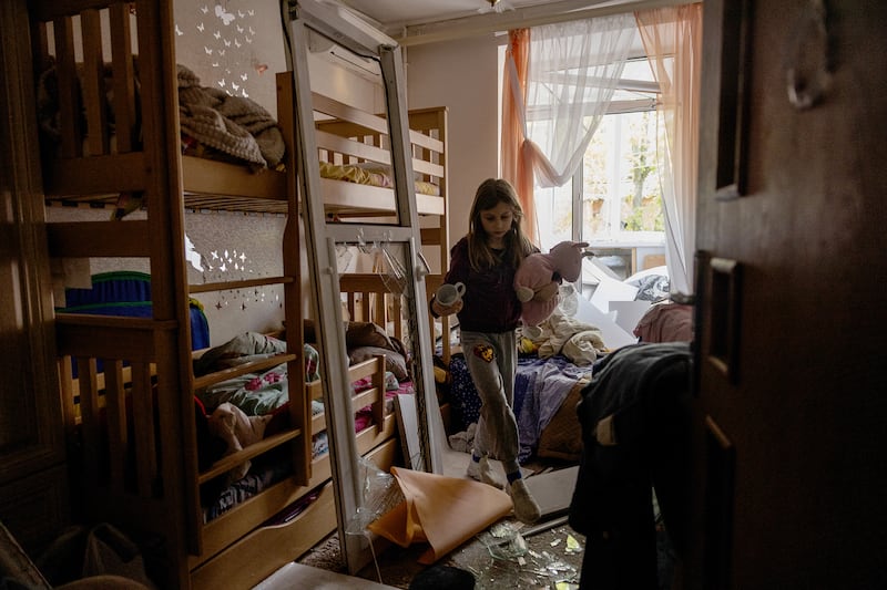 A girl carries toys in her damaged room following a Russian missile attack in Kyiv on April 24, 2025.