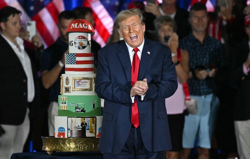 Donald Trump gestures by his birthday cake in 2024.