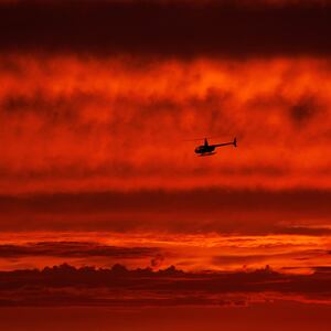 A helicopter travels south along the coast after sunset over the ocean as Hurricane Hilary approaches Del Mar, California.