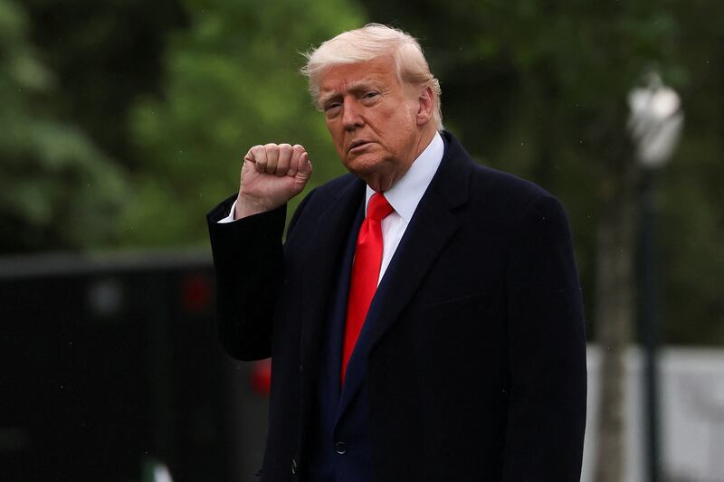 U.S. President Donald Trump raises a fist as he departs the White House to attend his meme coin gala