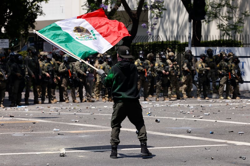 A demonstrator waves a Mexican flag in front of ICE officers in Los Angeles on June 7, 2025.