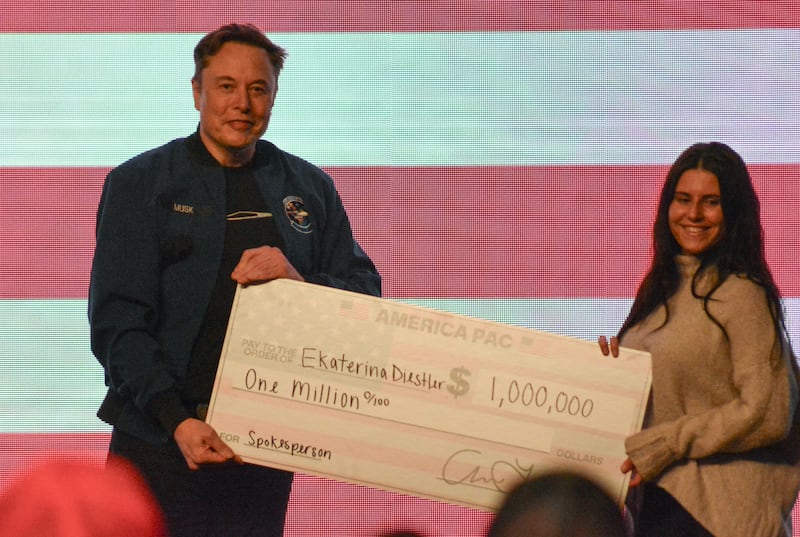 Elon Musk gives a $1 million check made to the order of Ekaterina Diesler during a town hall in Green Bay, Wisconsin on March 30, 2025.