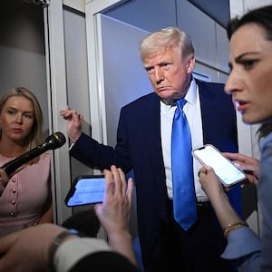 White House Press Secretary Karoline Leavitt listens as US President Donald Trump speaks to reporters on Air Force One.