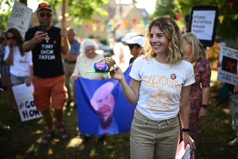 CHARLBURY, OXFORDSHIRE - AUGUST 12: A protestor holds a cake with a satirical image of US Vice-President JD Vance attached during a "Vance not welcome party", organised by Stop Trump Coalition supporters and local residents on August 12, 2025 in Charlbury, Oxfordshire. Following US President Donald Trump's recent holiday in Scotland, Vice President JD Vance and his family are spending their summer vacation in Chipping Norton in the Cotswolds. The idyllic, rural village is home to the former British Prime Minister David Cameron. Locals have been unprepared for the level of security disruption as roads are closed around the Vances' 6-acre country estate, and elderly people have been stopped from walking in the countryside by police. (Photo by Leon Neal/Getty Images)
