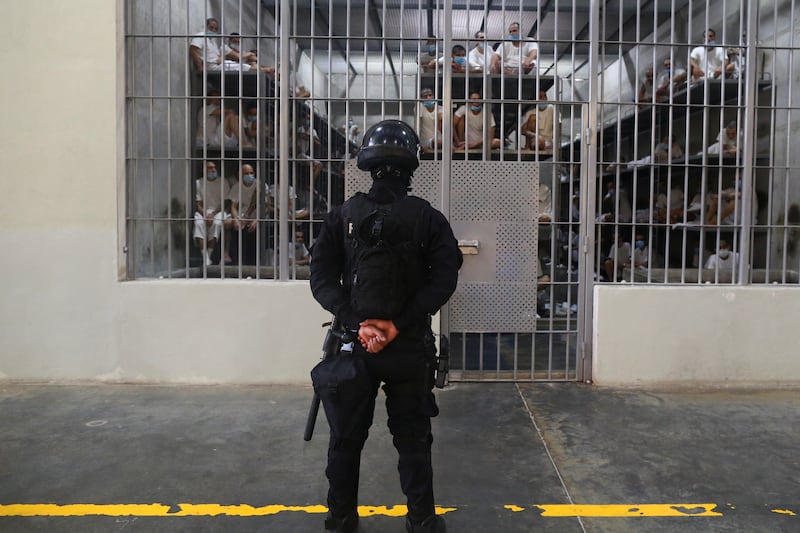 A policeman stands guard next to inmates inside a cell at the Terrorism Confinement Center (CECOT) prison, in Tecoluca, El Salvador April 4, 2025.